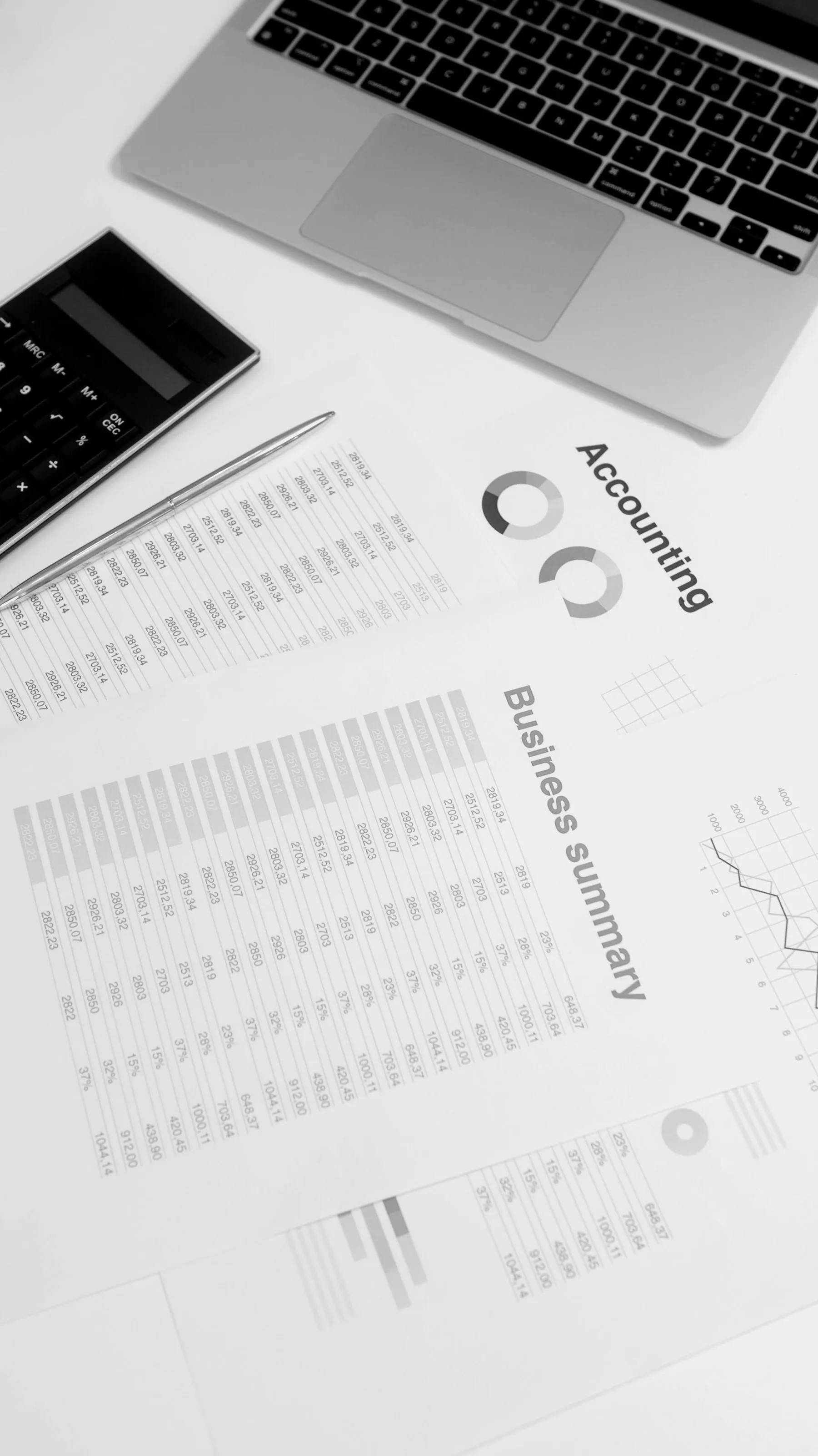 Dokumenty księgowe i zestawienie finansowe obok laptopa i kalkulatora