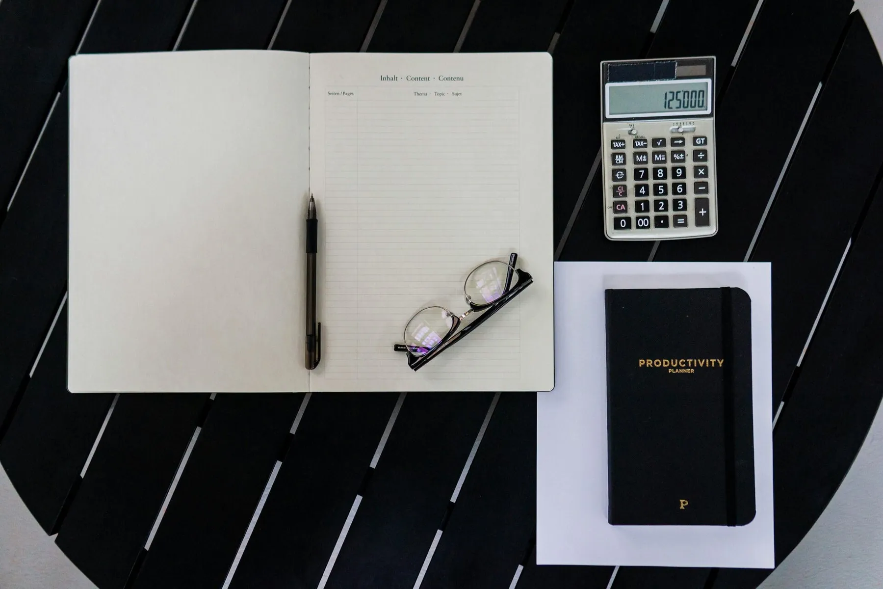 Otwarty notes, kalkulator i terminarz na ciemnym stole