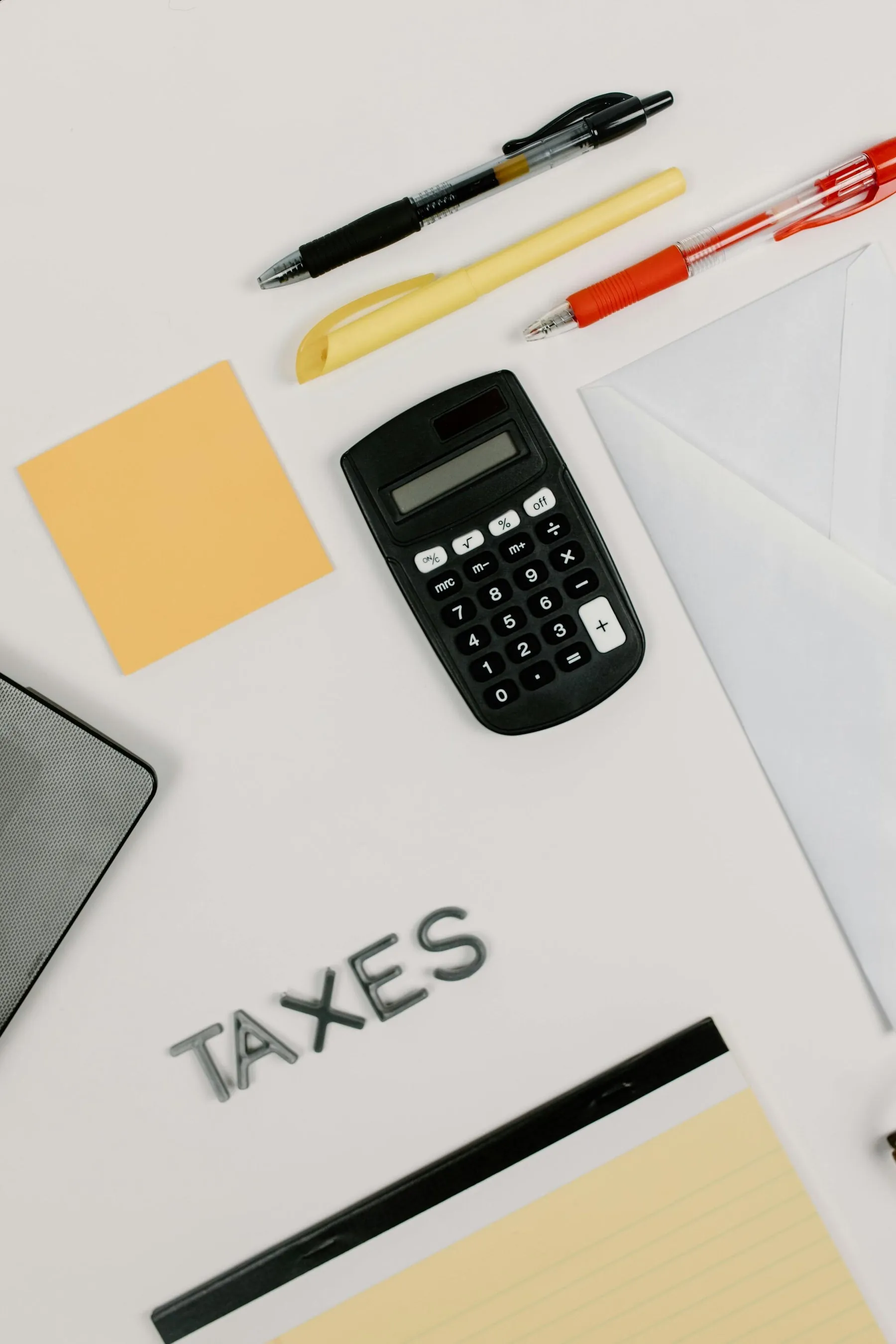 Kalkulator, długopisy i dokument z napisem TAXES