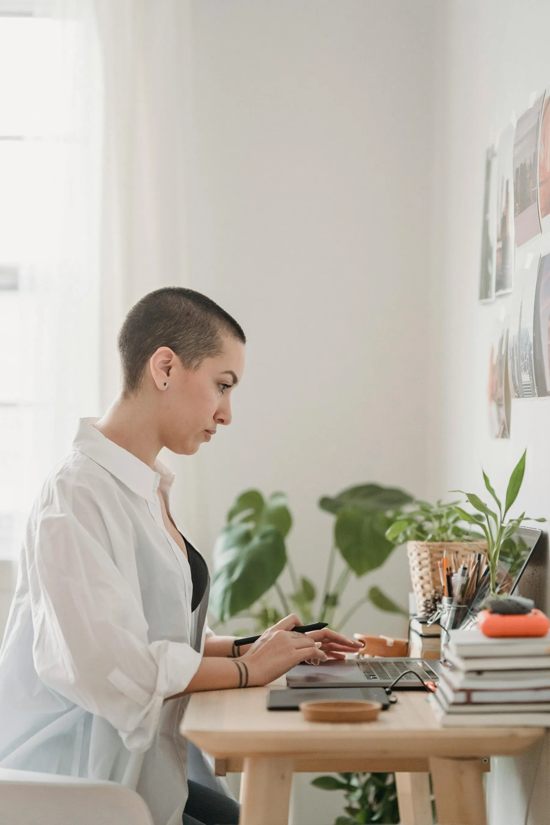Kobieta pracuje przy laptopie w jasnym biurze z roślinami